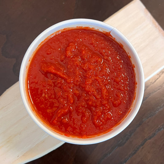 Red sauce in a white container on a wooden surface